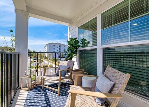 a porch with two chairs and a table and a window at Altis Grand Suncoast Apartments, Florida