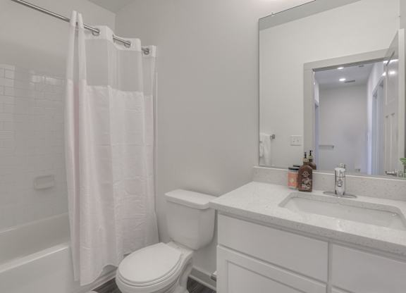 A white bathroom with a toilet, sink, and shower curtain.