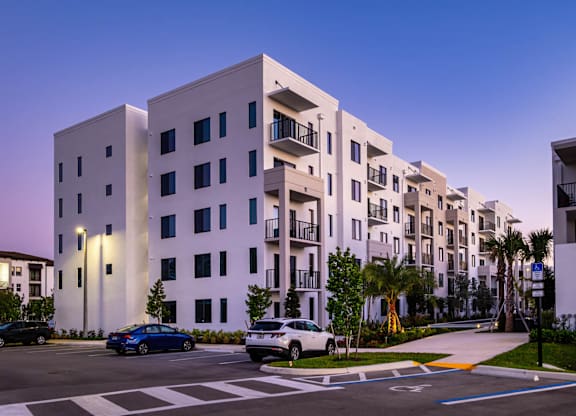 A modern apartment building with cars parked in front.