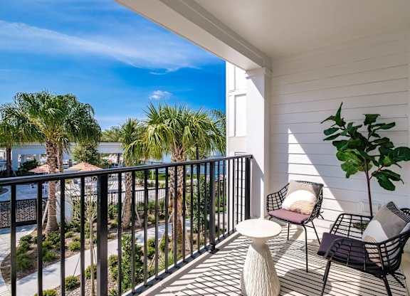 a balcony with two chairs and a table and a view of the water at Altis Twin Lakes Apartments, Florida