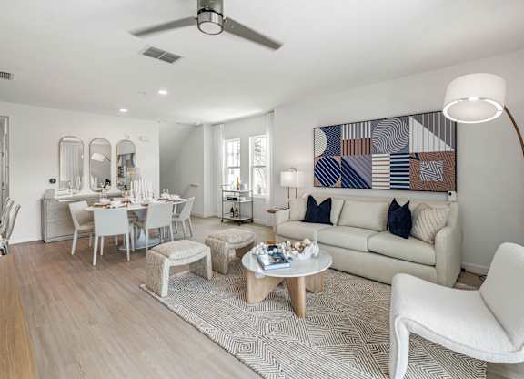 A living room with a white couch, a coffee table, and a large abstract painting on the wall.