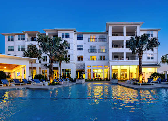 A large white building with a pool in front of it.
