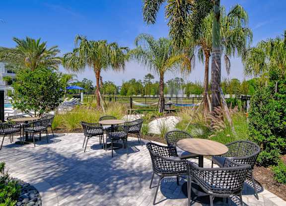 a patio with tables and chairs and palm treesat Altis Grand Lake Willis, Orlando Florida