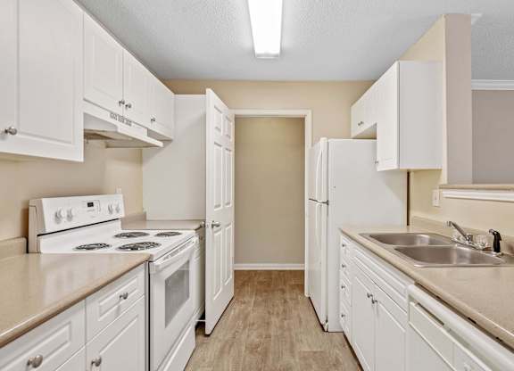 A kitchen with white cabinets and appliances.