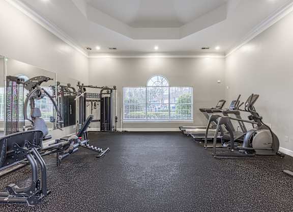 A spacious home gym with a variety of exercise equipment and a large window.