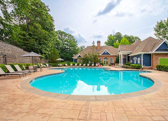 A large swimming pool surrounded by a brick patio and lounge chairs.
