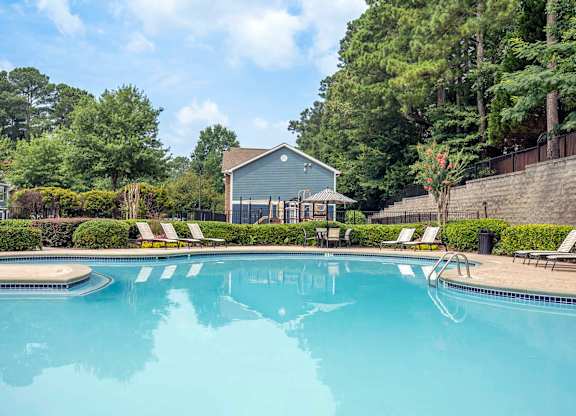 A swimming pool surrounded by trees and a house.