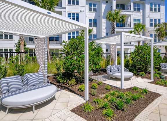 a patio with lounge chairs and hammocks in front of a building at Altis Grand Lake Willis, Florida