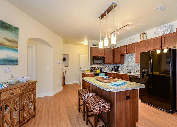 A kitchen with wooden cabinets and a black refrigerator.