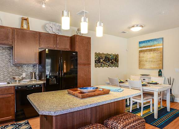 A kitchen with a refrigerator, sink, and dining table.