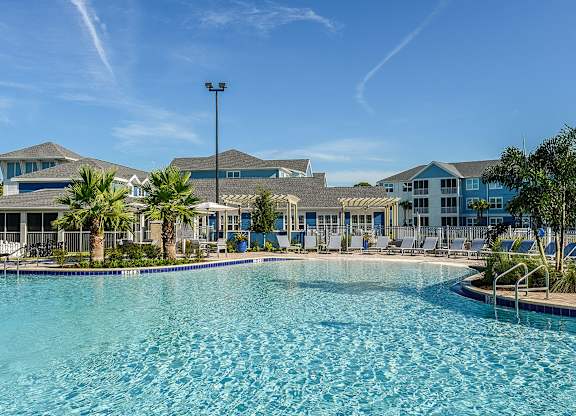 A swimming pool in front of a resort with palm trees.