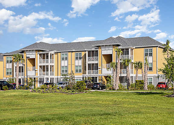 A large yellow building with a grassy area in front.