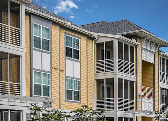 A building with yellow and white siding and a balcony.