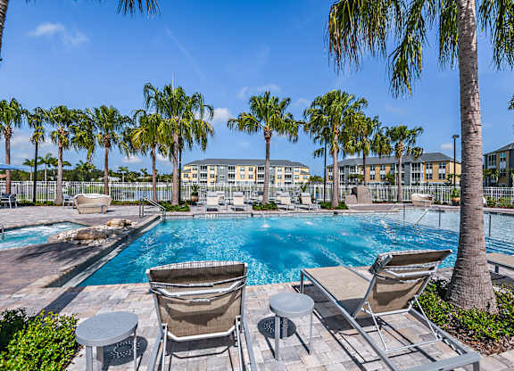 A pool surrounded by palm trees and lounge chairs.
