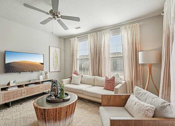 A living room with a television, a sofa, a coffee table, and a painting on the wall.