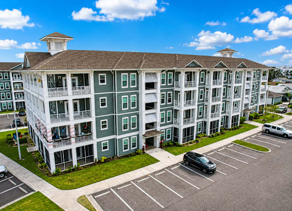 A large white building with a green trim and a parking lot in front.