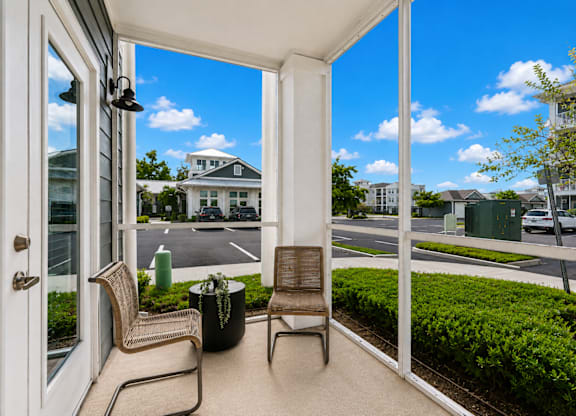 A patio with a chair and table is overlooking a street.