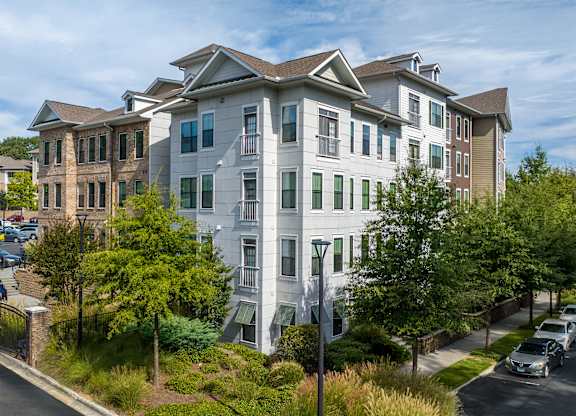 A white apartment building with a green lawn in front.