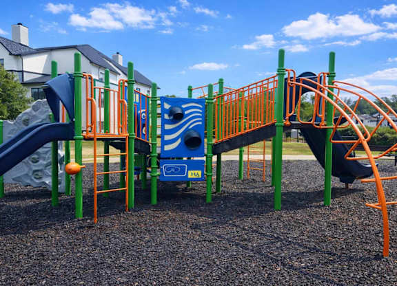 A playground with a blue slide and orange railings.