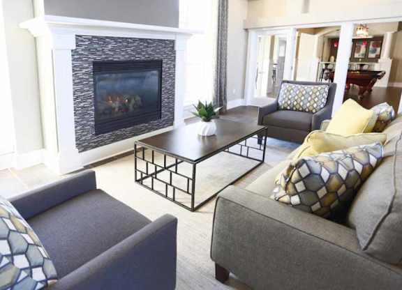 A living room with a fireplace and a grey couch.