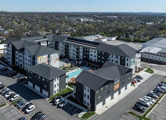 an aerial view of an apartment complex with a swimming pool and parking lot