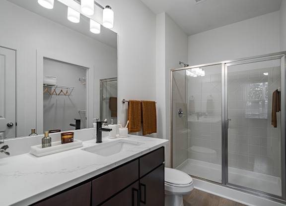 A modern bathroom with a white countertop and a walk-in shower.