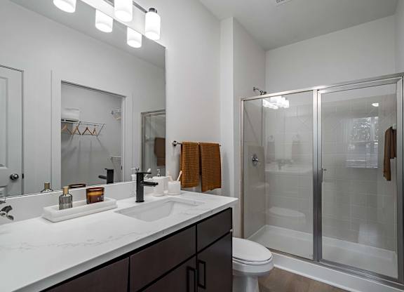 A modern bathroom with a white countertop and a walk-in shower.