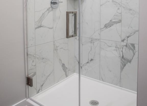 A white shower with a marble tile wall.
