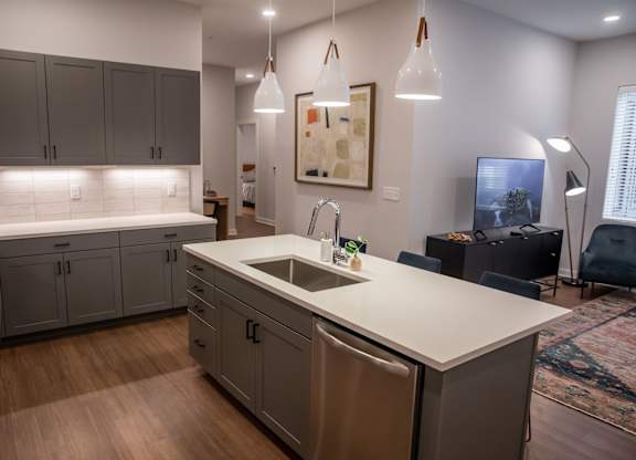 A kitchen with a white counter top and grey cabinets.