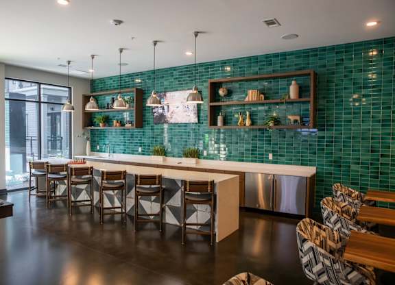 A modern kitchen with a green tiled backsplash and wooden furniture.