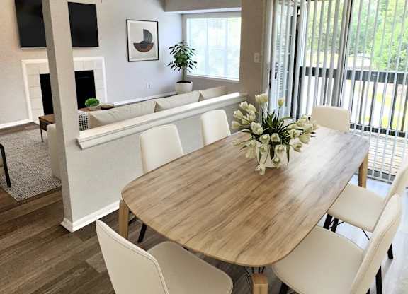 A dining room with a wooden table and white chairs.