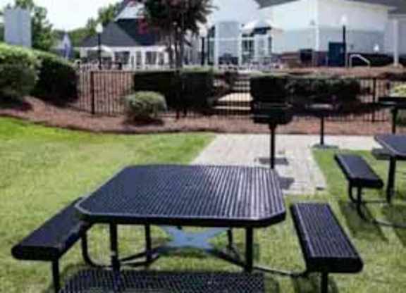 A black picnic table with two benches is in the foreground of a grassy area.
