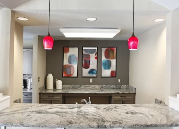 A kitchen with a marble countertop and black chairs.