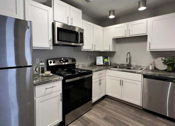 Apartments in Charlotte, NC, with In-Unit Washer and Dryer - Coffey Creek - A Modern Kitchen With White Shaker Cabinets, Stainless Steel Refrigerator, Electric Range, And A Double Sink.