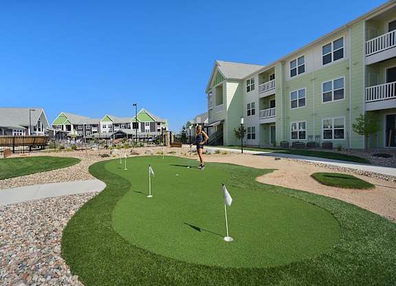 A person is playing mini golf on a sunny day.