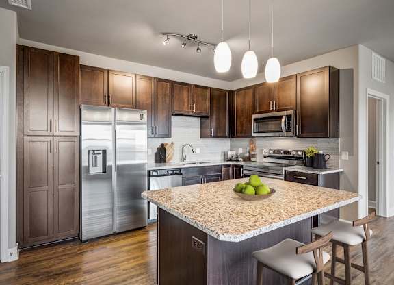 A kitchen with a granite countertop and a bowl of green apples on it.