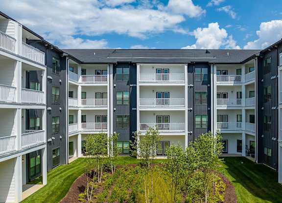 an exterior view of an apartment building with grass and trees