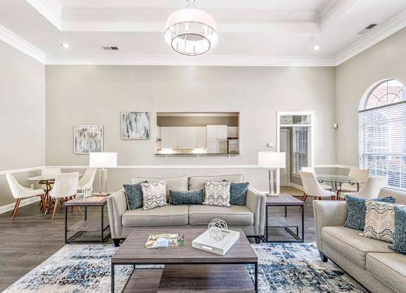 A modern living room with a grey sofa, a coffee table, and a large window.