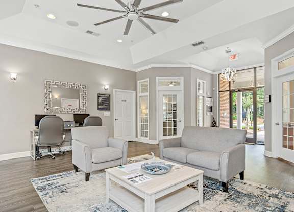 A living room with a white ceiling fan and grey couches.