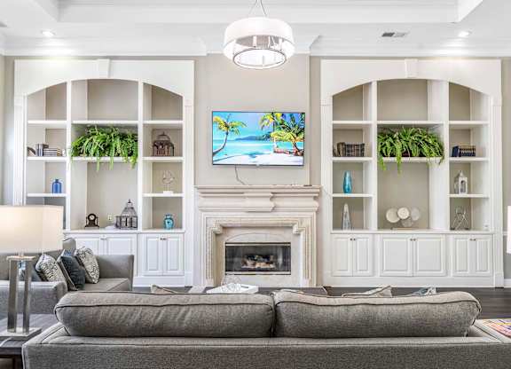 A living room with a grey couch and a fireplace.