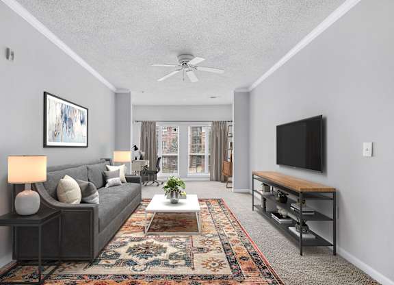 A living room with a grey couch, a rug, a ceiling fan, and a flat screen TV.