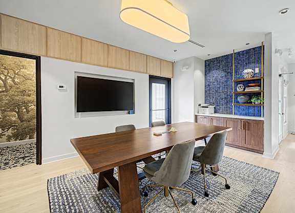 A modern dining room with a wooden table and grey chairs.