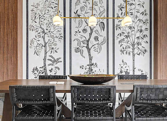 Four black chairs are arranged around a table in front of a wall with a floral mural.