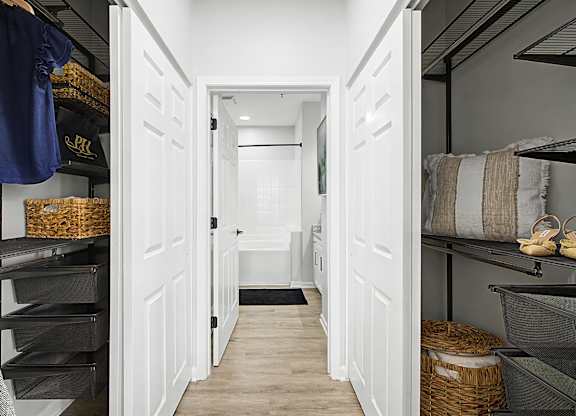 A walk in closet with white doors and shelves.