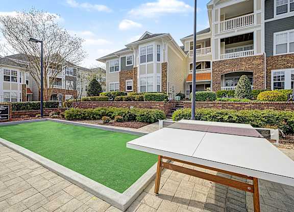 A table tennis table is in the middle of a courtyard with apartment buildings in the background.
