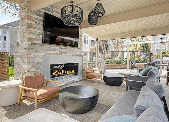 A patio with a fireplace and chairs.