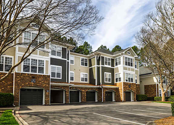 A large, modern apartment building with a parking lot in front.
