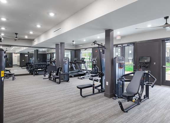 3-Bedroom Luxury Apartments in East Nashville, TN - Flats at Laurel and Pine - Fitness Center with Strength Training Equipment, Free Weights, Cardio Machines, Ceiling Fans, Mirror Wall, and Floor-to-Ceiling Windows.