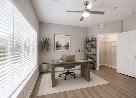 A room with a desk, chair, and a plant.