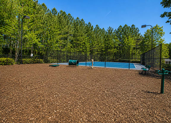 A tennis court surrounded by trees and a fence.
